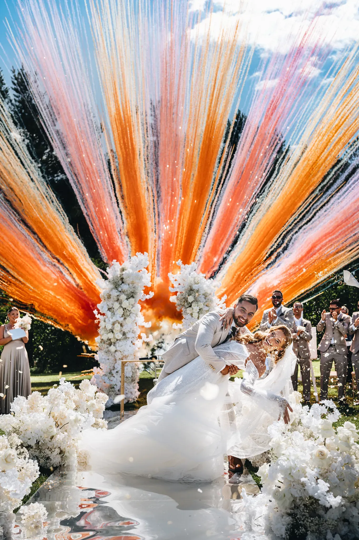 szczesliwa i usmiechnieta para mloda na tle wystrzalu z kolorowych rac na slubie plenerowym w hotelu nad jeziorem , fotograf studio grygierczyk