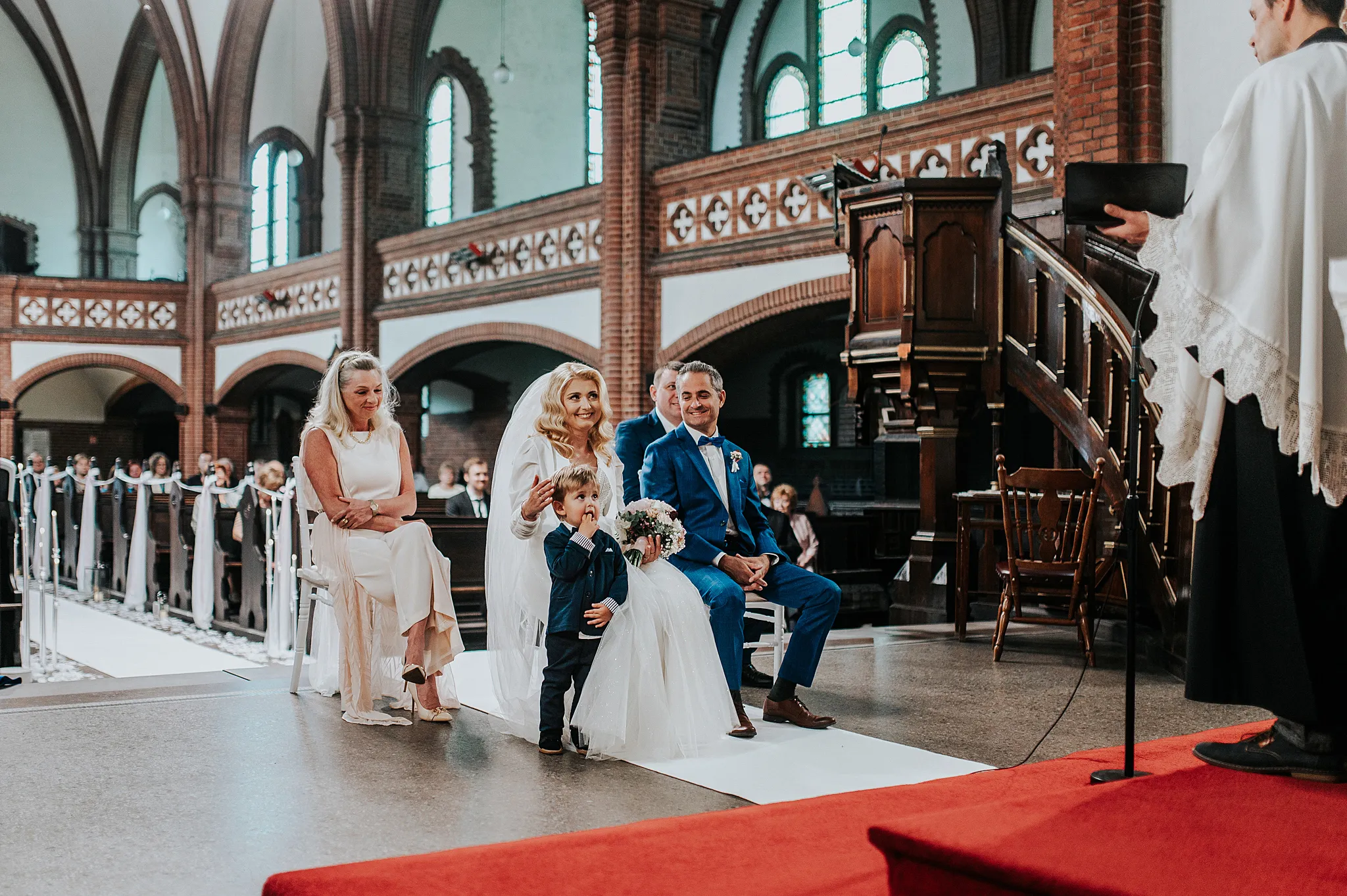 para mloda w kosciele podczas cermoni z radossnymi zaciekawionym synem stojacym obok matki. Kościół Rzymskokatolicki pw. św. Anny