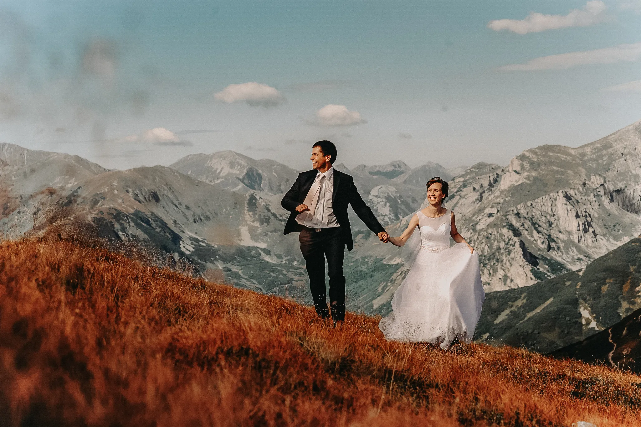 para mloda na sessji slubnej w gorach biegnie w kierunku slonca . w tle pastelowe tatry kasprowy wierch studio grygierczyk