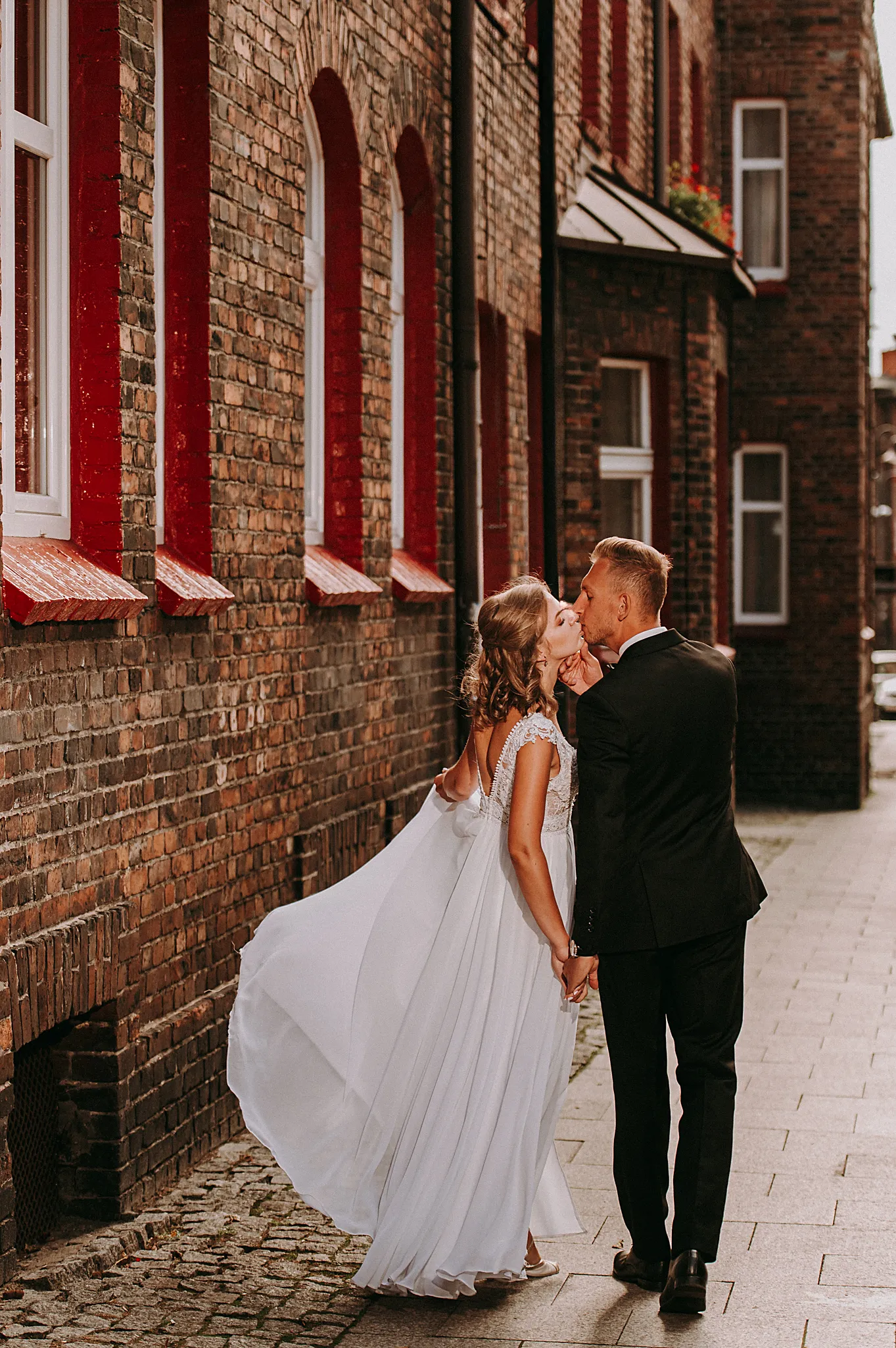 pan mlody caluje mloda pania podczas spaceru na zabytkowej dzielnucy nikiszowca w godzinach kiedy zahodzi slonce